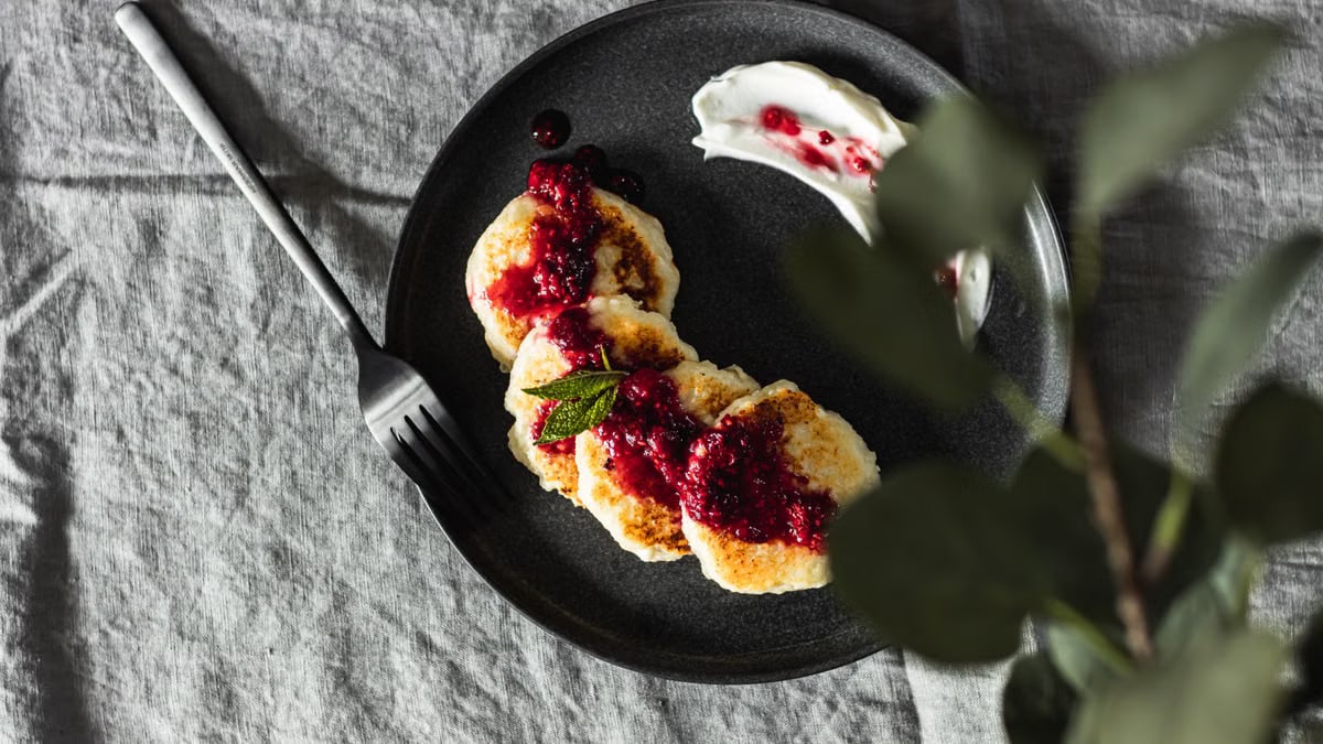 A tempting plate of pancakes topped with berry jam and sour cream, ideal for breakfast.