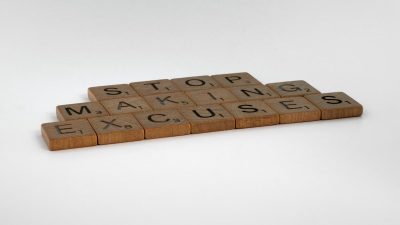 Inspirational phrase "Stop making excuses" crafted with wooden letter tiles.